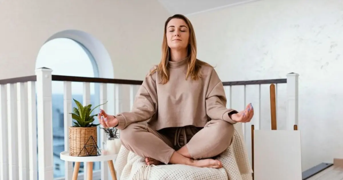 Pessoa meditando em casa em posição de lótus, demonstrando como praticar mindfulness para alcançar equilíbrio e paz interior.