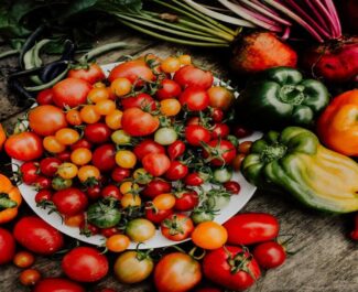 Variedade de legumes frescos, incluindo tomates e pimentões, colhidos de uma horta orgânica no apartamento.