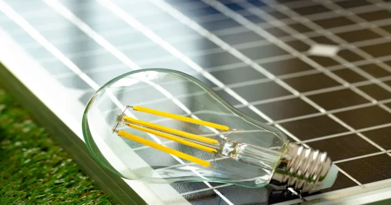 Lâmpada acesa sobre painel solar, representando a energia solar como fonte de luz e eletricidade.