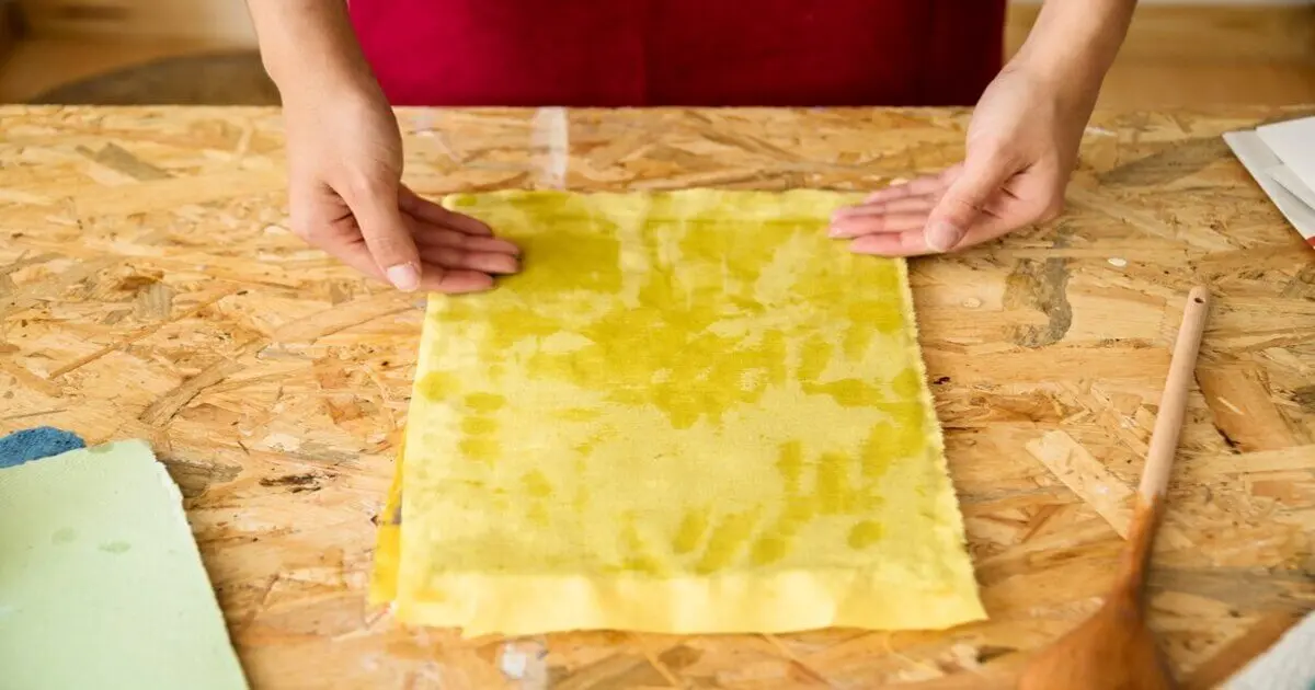 Mãos ajustam wraps de cera de abelha recém-feitos sobre mesa de madeira, destacando alternativa sustentável ao plástico filme.