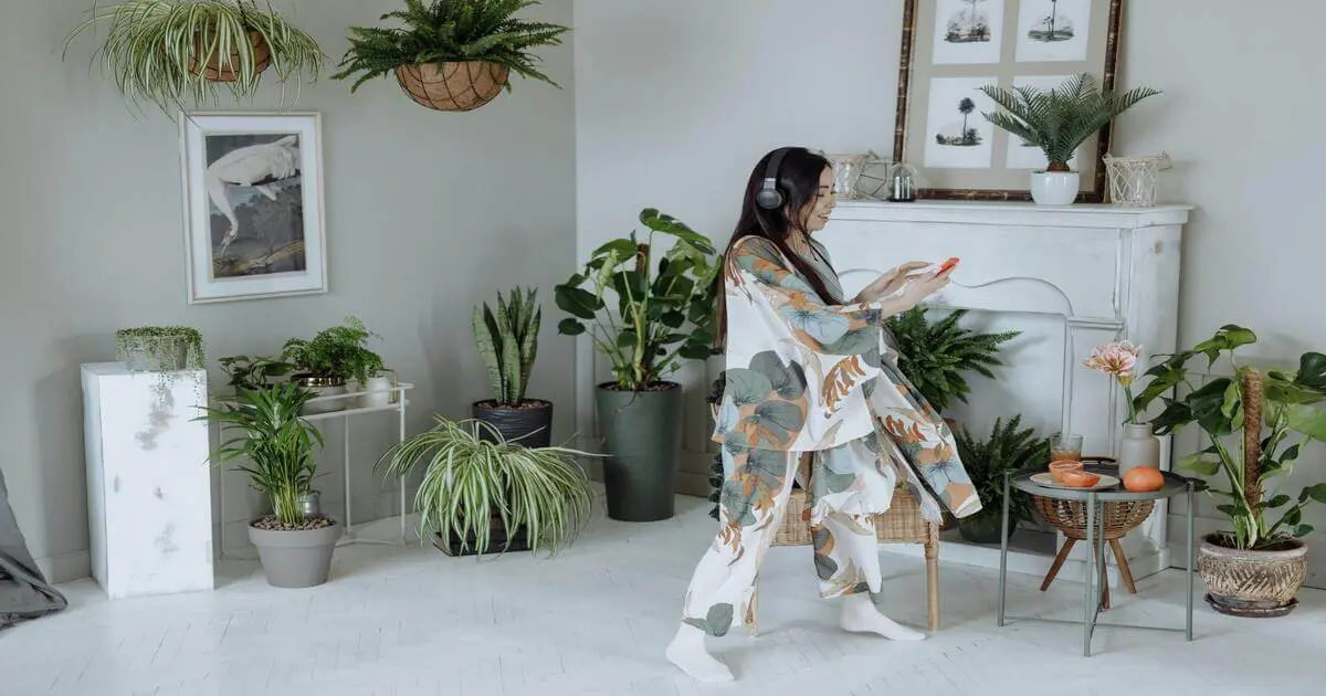 Mulher em ambiente minimalista cercado por plantas, ouvindo música e relaxando. Minimalismo em casa traz harmonia e bem-estar.