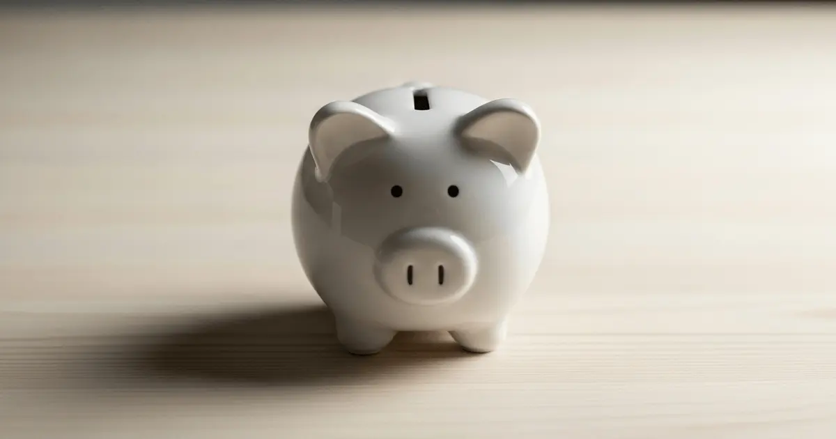 Cofre porquinho branco sobre mesa de madeira simbolizando dinheiro parado sem render e a importância de investir melhor.