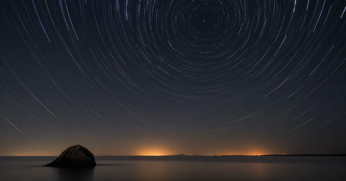 Rastros de estrelas girando ao redor de um ponto fixo no céu noturno, a testemunha imóvel enquanto tudo se move.